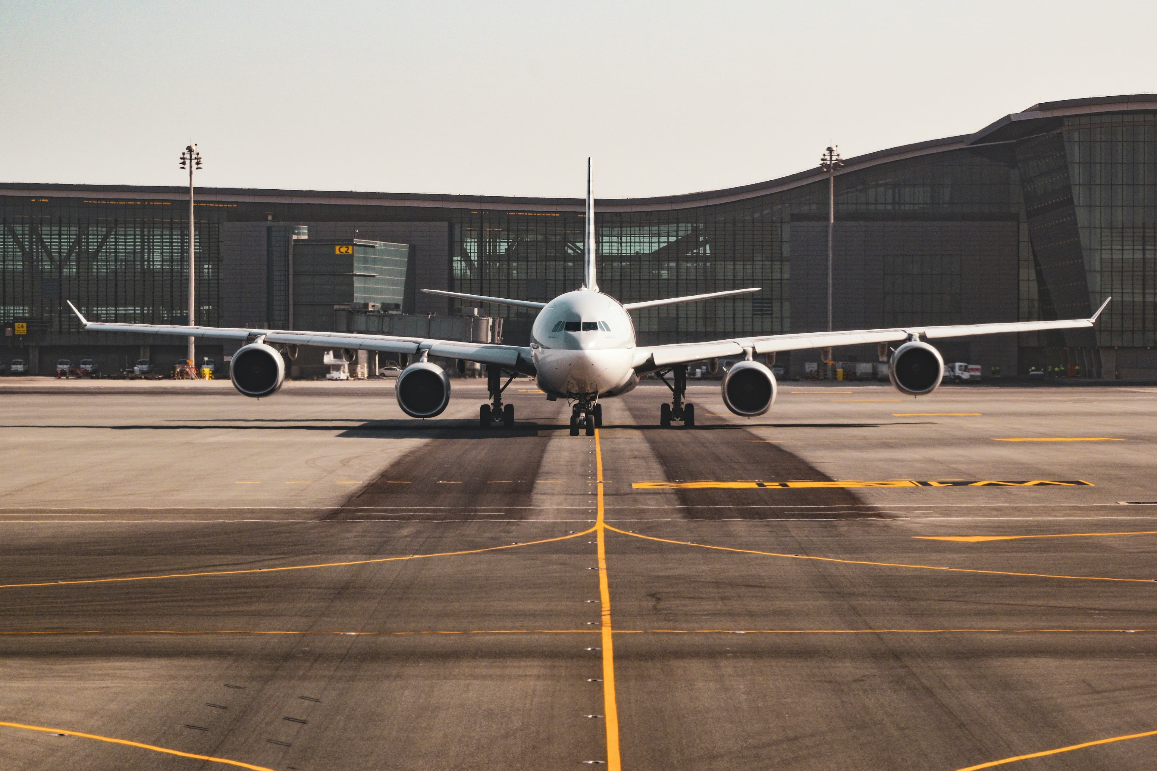 Wide-body commercial aircraft taxiing head-on in front of a modern airport terminal